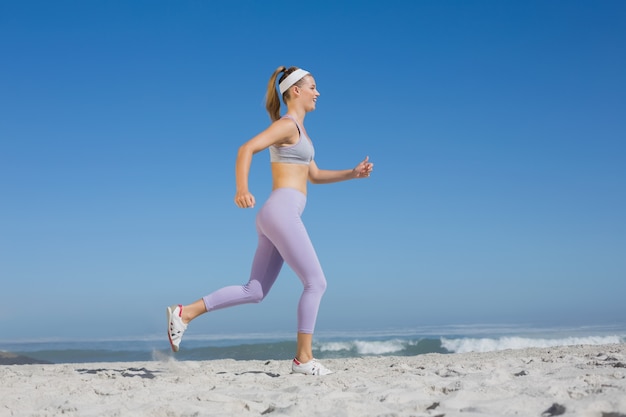 Loira desportiva na praia jogging