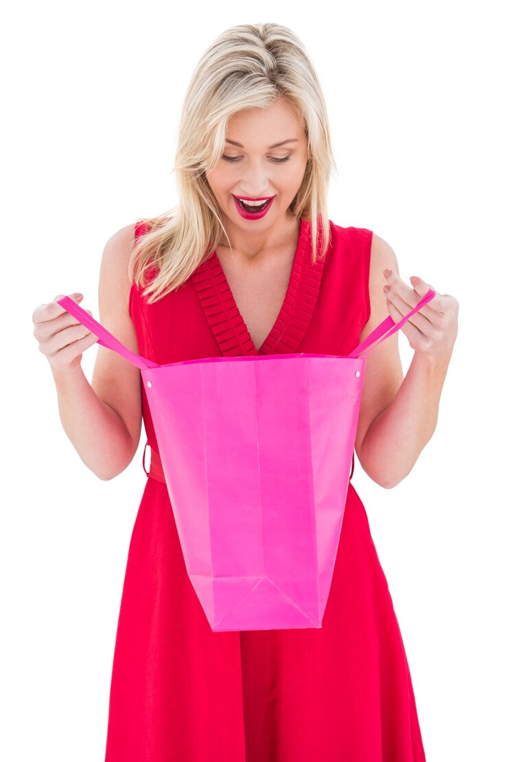Foto loira elegante em vestido vermelho, abrindo o saco de presente