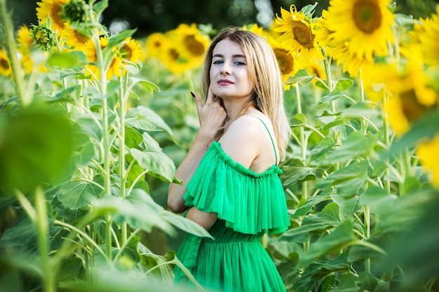 Loira europeia com um vestido verde na natureza com girassóis