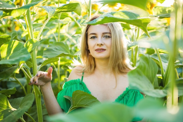 Loira europeia com um vestido verde na natureza com girassóis