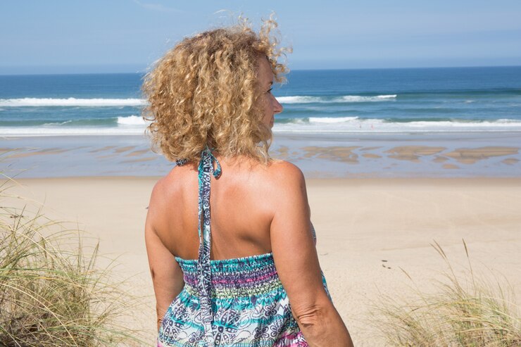 Foto loira feliz em pé no mar, posando em um dia ensolarado