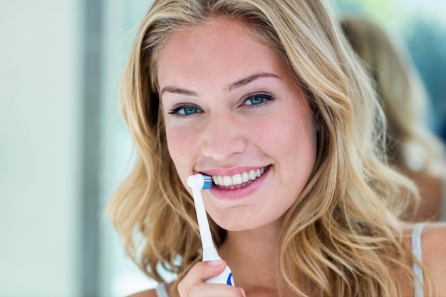 Loira feliz escovando os dentes no banheiro em casa