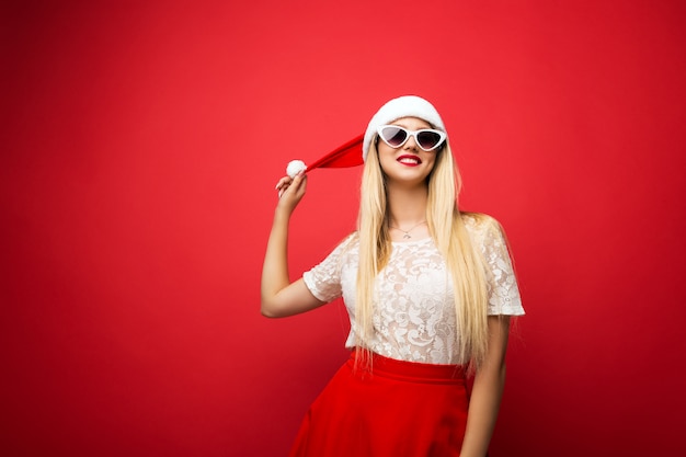 Loira feliz no chapéu de Papai Noel em fundo vermelho isolado