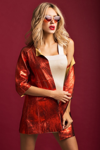 Loira glamourosa posando com uma jaqueta de couro vermelha