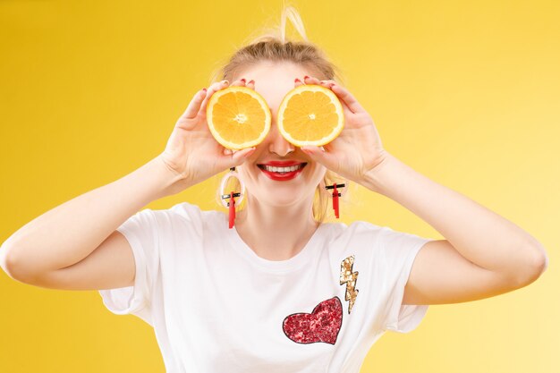 Loira jovem alegre posando com laranjas frescas