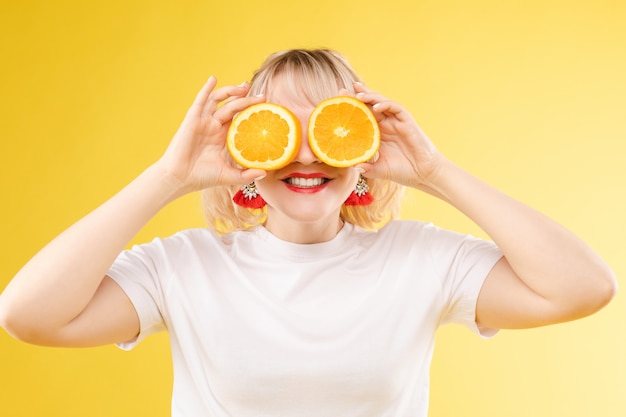 Loira jovem alegre posando com laranjas frescas