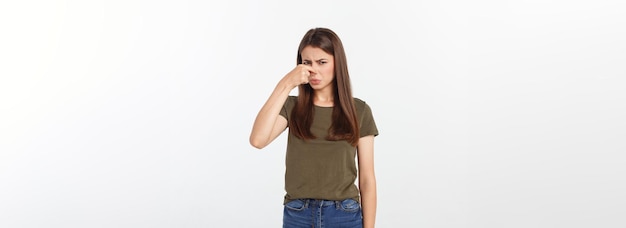 Foto loira jovem enojada fechando o nariz com os dedos isolados sobre fundo branco