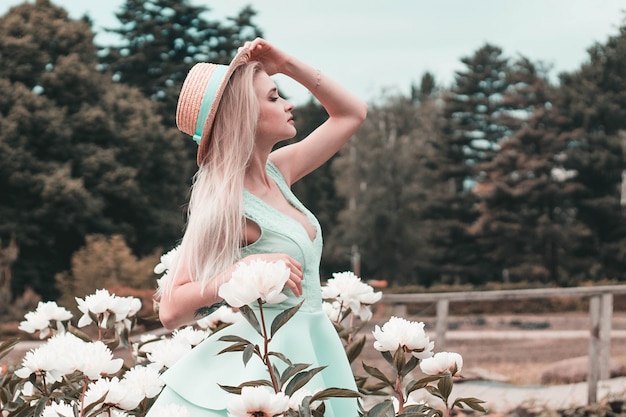 Loira jovem mulher em um vestido de bétula em um jardim floral, correção de cor na moda