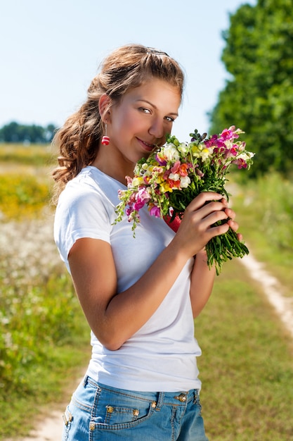 Loira linda com um buquê de flores silvestres ao ar livre