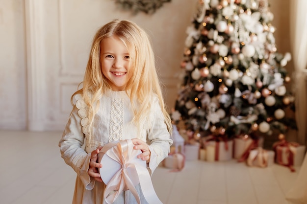 Loira linda com um vestido perto da árvore de Natal