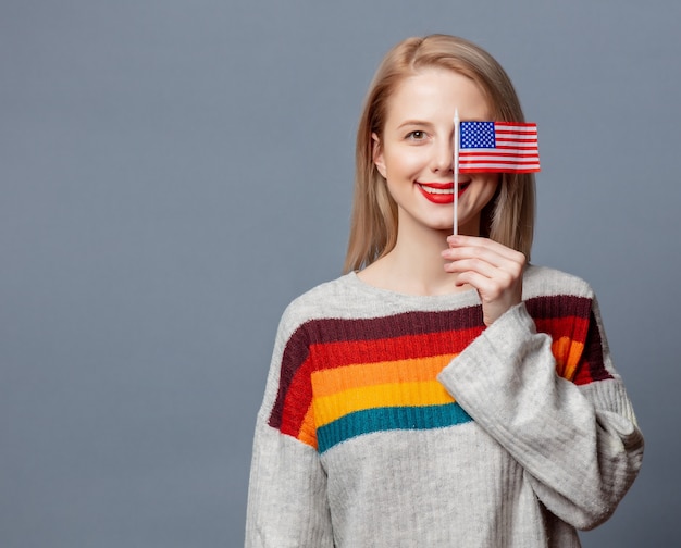 Loira linda em suéter com bandeira dos EUA em cinza