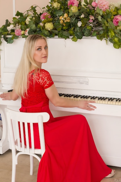 Loira linda em um vestido vermelho ao piano