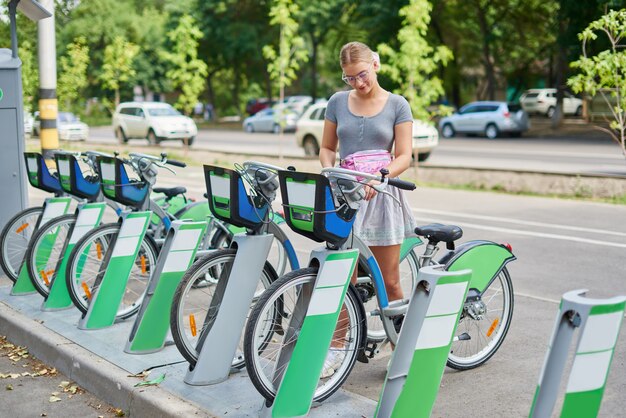 Loira linda garota atlética em uma saia alugar uma bicicleta em Almaty