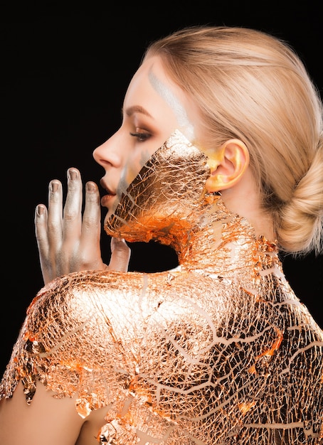 Foto loira luxuosa com maquiagem criativa e folha de ouro no pescoço e nas costas