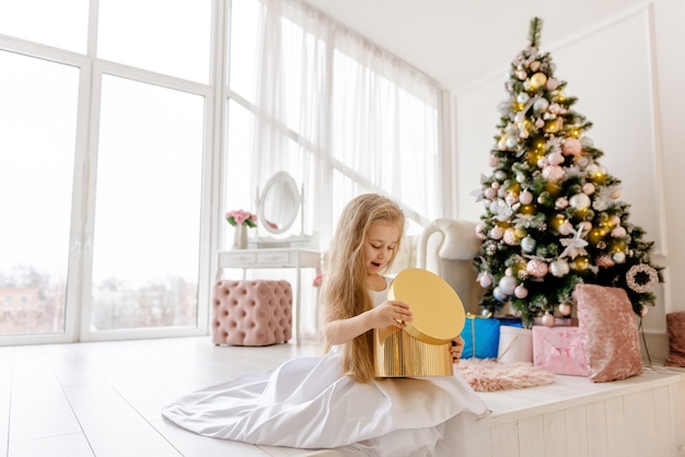 Loira menina bonitinha abre um presente de Natal. Feliz Natal bebê.