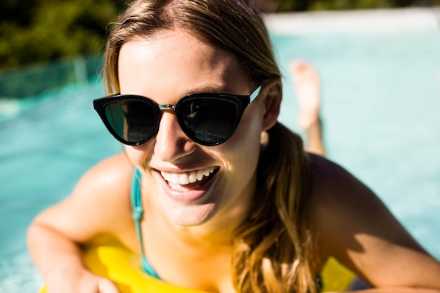 Loira sorridente com inflável na piscina