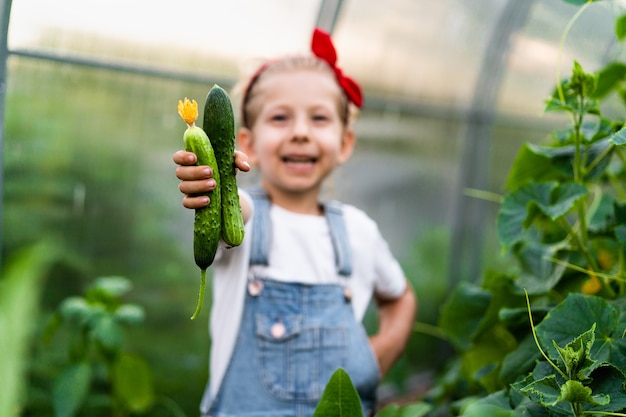 Loirinha feliz em uma estufa com pepinos nas mãos planta conceito de jardinagem para