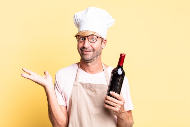 loiro bonito chef adulto homem segurando uma garrafa de vinho