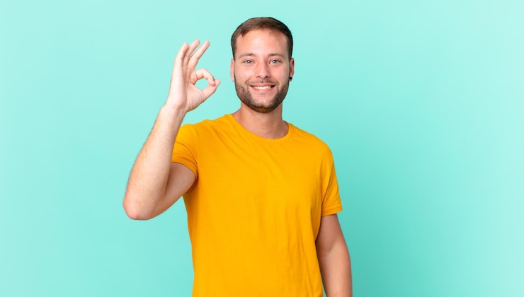 Foto loiro bonito se sentindo feliz, mostrando aprovação com um gesto de ok