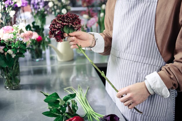 Loja de flores. Florista competente em seu local de trabalho enquanto compõe ikebana