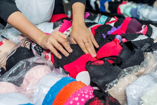 Loja de roupa íntima, mãos femininas com sutiãs coloridos