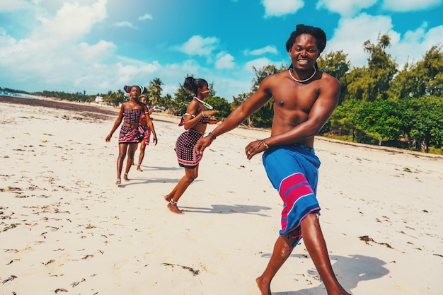 Lokale Gruppe von Menschen mit typisch kenianischer Kleidung, die am Strand tanzt