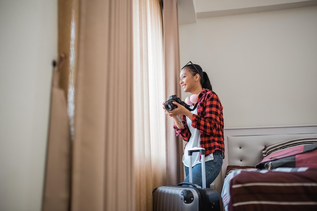 Lokale Touristin fängt die Landschaft mit einer Kamera durch das Fenster im Hotel ein