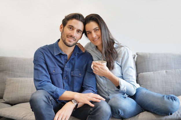 Lokalisierte herrliche lächelnde Paare im Denim auf bequemer Couch