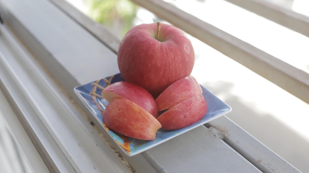 Lokalisierter roter Apfel Nasse Früchte nahe bei einigen geschnittenen Äpfeln auf blauem platexA