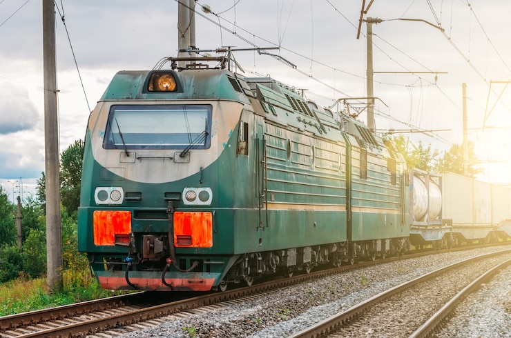 Foto lokomotive elektrisch mit einem güterzug bei hochgeschwindigkeitsfahrten auf der schiene.
