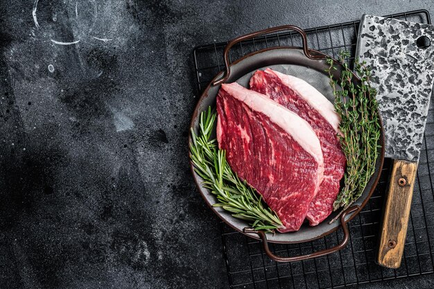 Lombo cru ou bife de carne Picanha em uma bandeja de aço Fundo de madeira preta Vista superior Copiar espaço