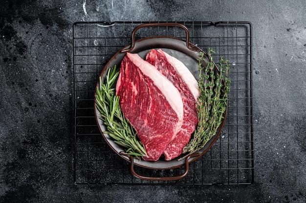 Lombo cru ou bife de carne Picanha em uma bandeja de aço Fundo de madeira preta Vista superior