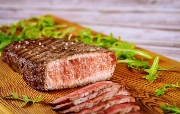 Lombo de carne rara médio com rúcula na placa de corte.