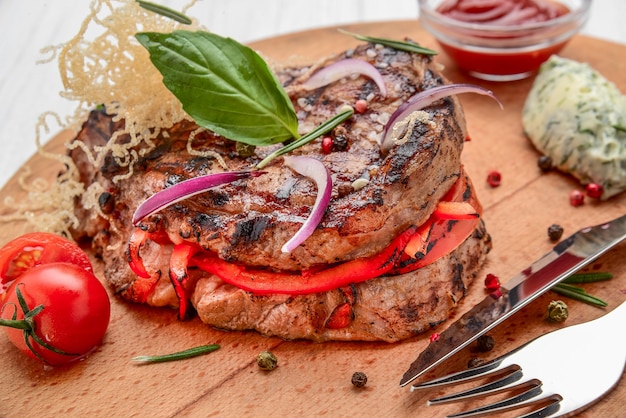 Lombo de porco assado com tomate e temperos em uma mesa de madeira