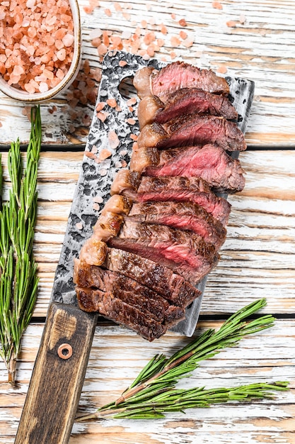 Lombo grelhado ou bife de picanha em um cutelo com ervas. Vista superior branca.