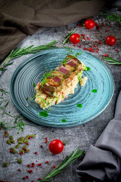 Lomo de atún frito con cuscús y hierbas sobre una mesa de piedra grisxA