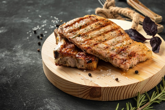 Lomo de cerdo a la parrilla sobre una plancha de madera sobre una superficie oscura