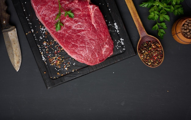 El lomo de res crudo se encuentra en una mesa negra de tablero de madera marrón