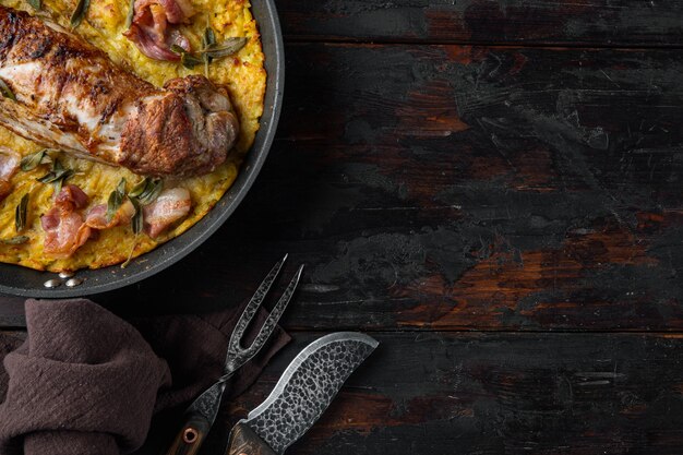 Lomo de solomillo de cerdo al horno con patatas y hierbas en sartén de hierro fundido con cuchillo de barbacoa y tenedor de carne