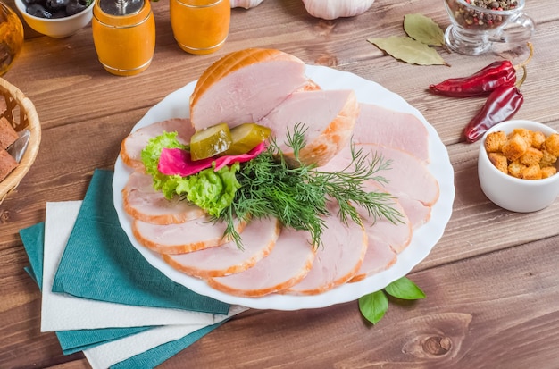 Lonchas de jamón en un plato blanco sobre un fondo de madera oscura.