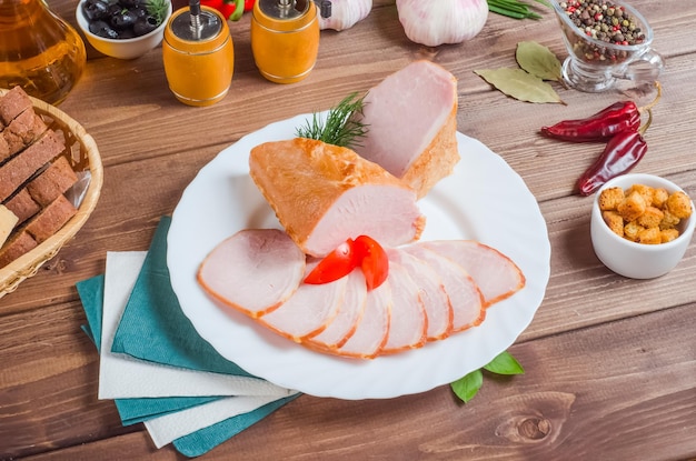 Lonchas de jamón en un plato blanco sobre un fondo de madera.