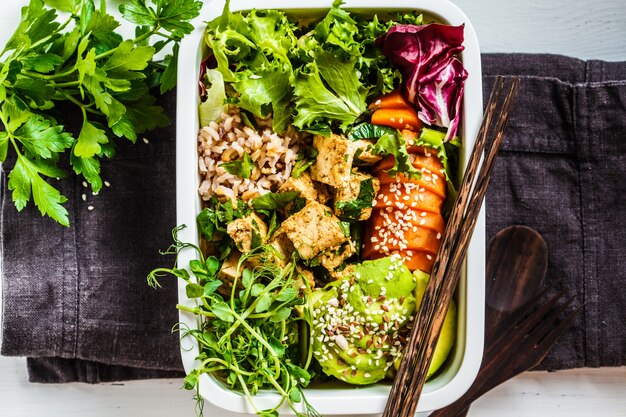 Lonchera con comida vegana saludable. bento box con arroz, camote, tofu y verduras.