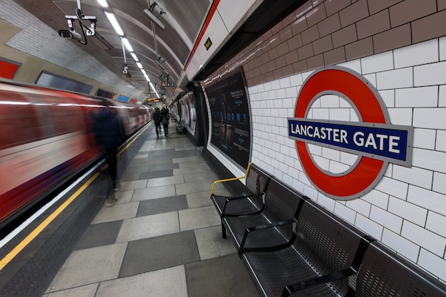 Londoner U-Bahn-Zeichen mit fahrendem Zug und Menschen an der Lancaster Gate Station