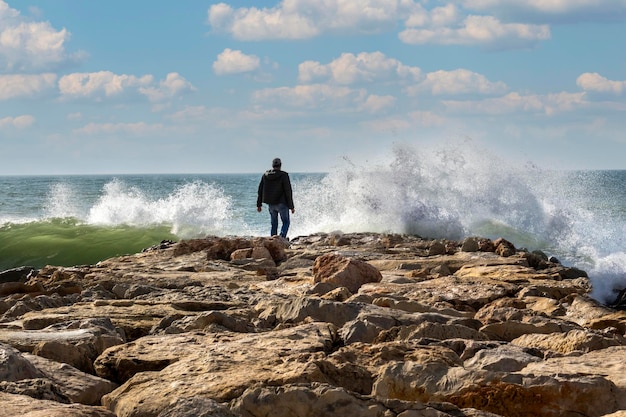 Loney man en rompeolas salpicando olas