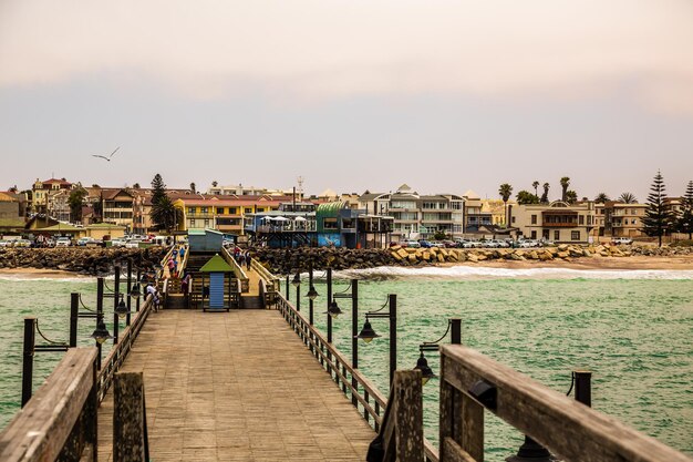 Long pier poca gente casas residenciales en la costa de la ciudad colonial alemana de Swakopmund Namibia