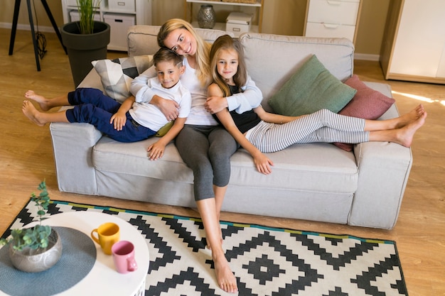 Foto long shot von mutter und kinder sitzen auf einer couch