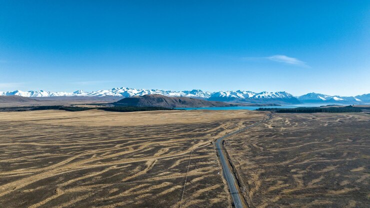 Foto longa estrada reta em uma paisagem agrícola em direção ao lago tekapo