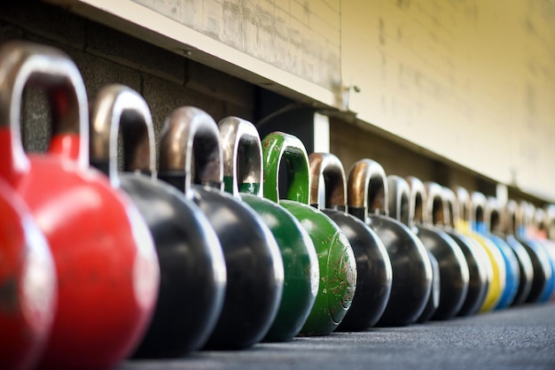 Longa fila de kettlebells pesados coloridos no ginásio com perspectiva decrescente.