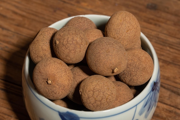 Longan seco no recipiente na mesa de grãos de madeira