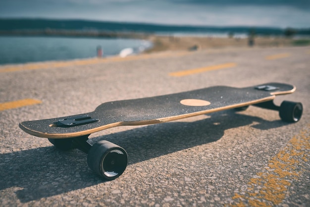 Longboard auf Asphalt vor dem Hintergrund des Meeres ohne Menschen